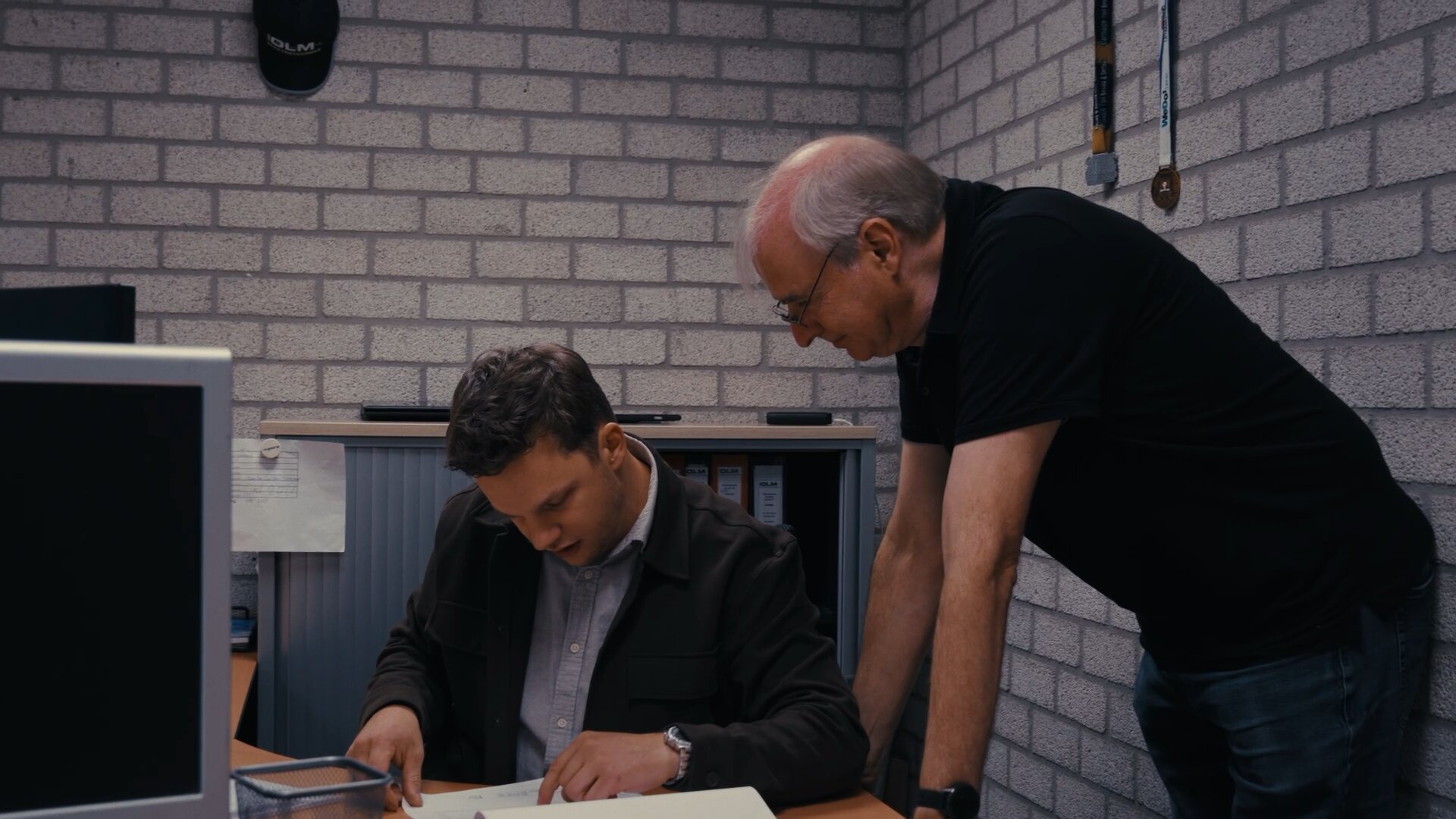 Twee collega's nemen samen een bestek door aan een bureau op kantoor.