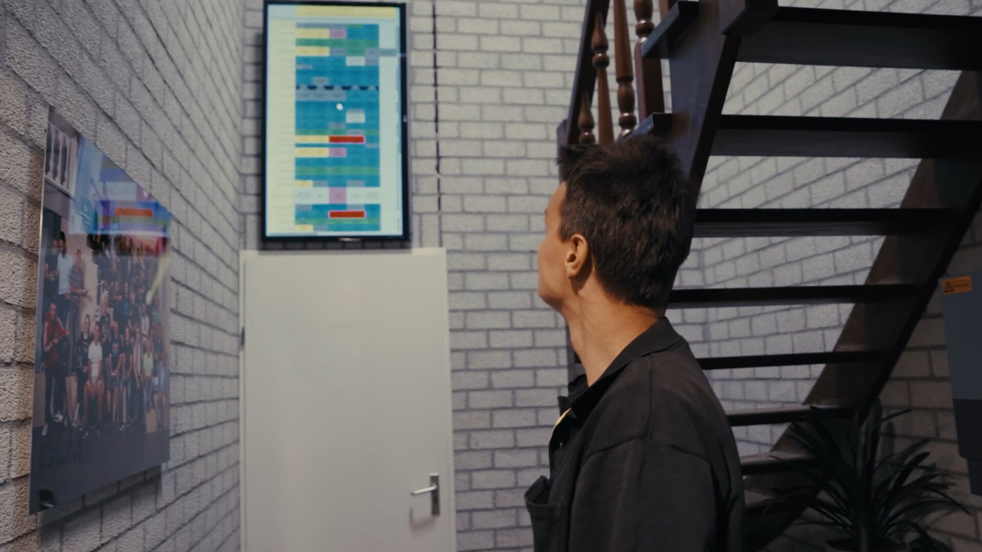 Collega bekijkt de planning op een scherm in de gang van het kantoor.