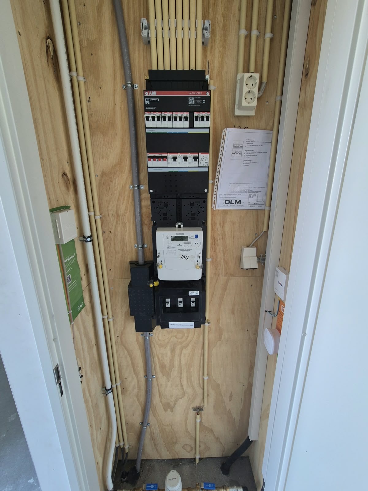 Nieuwe ABB-groepenkast met slimme meter in een meterkast, met het groepenschema van Van Olm ernaast.