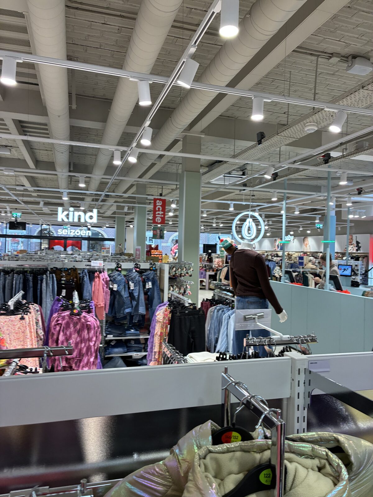 Kinderafdeling van de Hema met kledingrekken, verlichte belettering en spots aan het plafond.