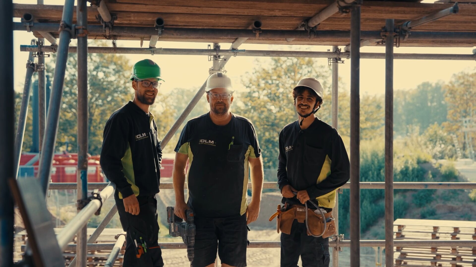 Drie monteurs van Van Olm staan lachend in de steigers van een woning in aanbouw.